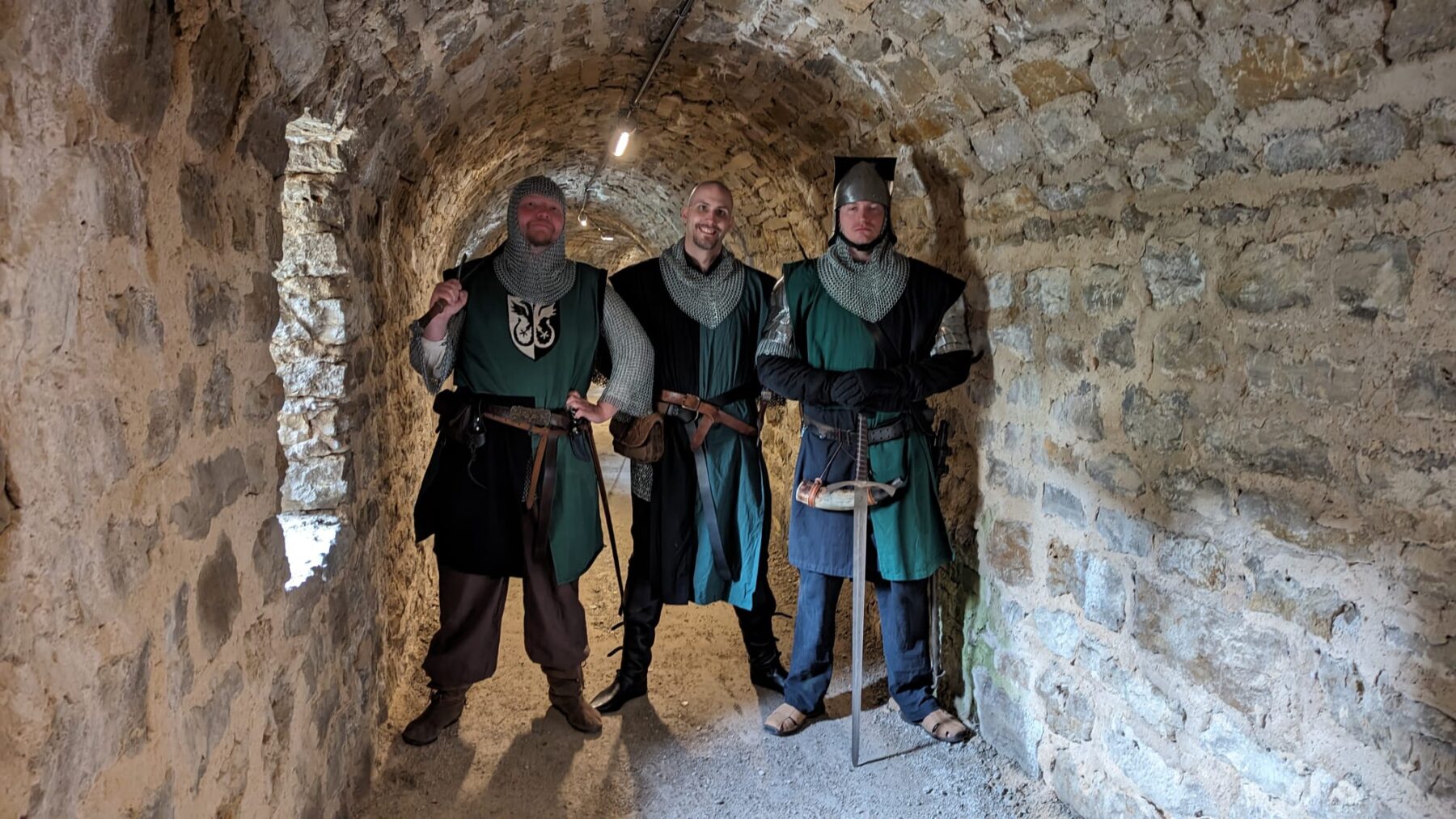 Drei Gewandete im gewölbten Burggang